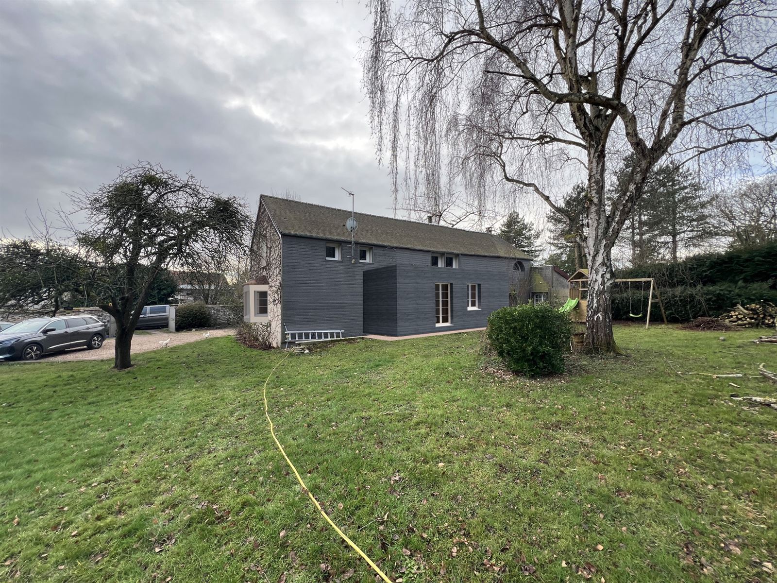 La maison, bardage bois foncé, à la campagne
